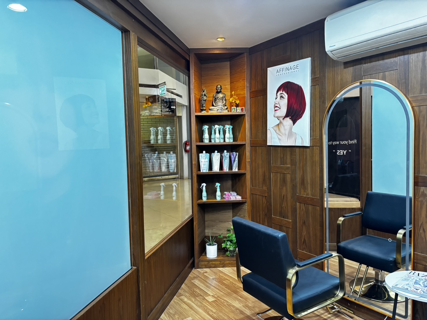 Corner shelving with a small Buddha shrine above the Keratin Water bottles, beside a lit arch mirror