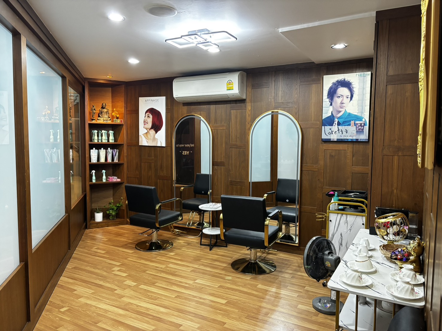 The second room — black and gold chairs on wood flooring between two arch mirrors, Affinage and Loretta posters on the panelling